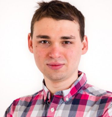 Maksym has a plaid shirt, short hair and looks both focused and relaxed into the camera.